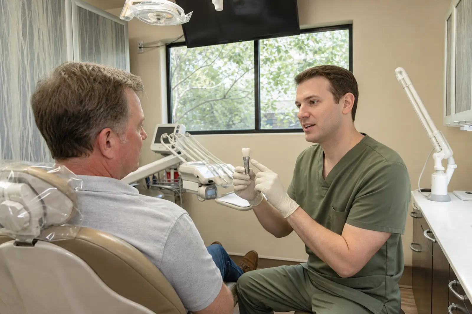 A dentist explaining a dental implant model
